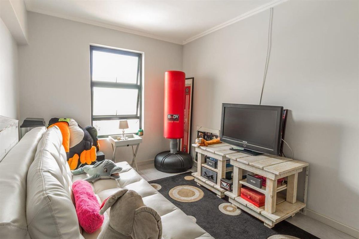 A compact living room featuring neutral walls and an aluminium-framed window, providing a functional space for relaxation.