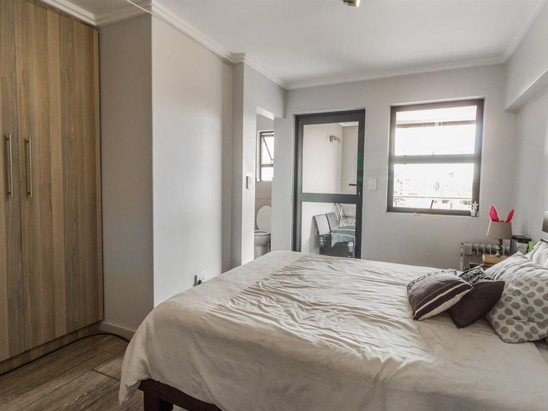 A well-maintained bedroom featuring a built-in wardrobe, neutral wall finishes, and direct access to an adjoining balcony area.