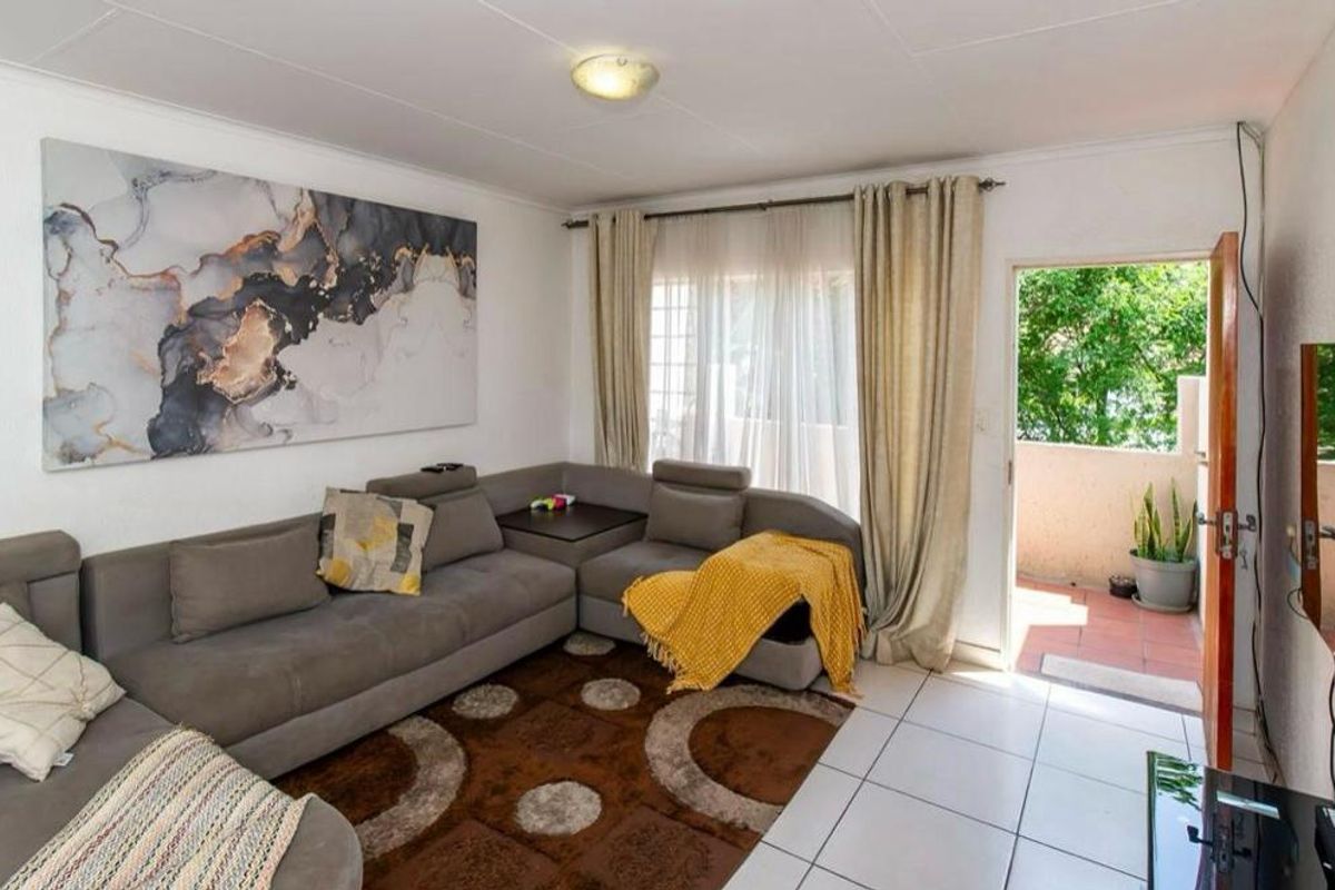 A bright living room featuring tiled flooring and direct access to an outdoor balcony area.