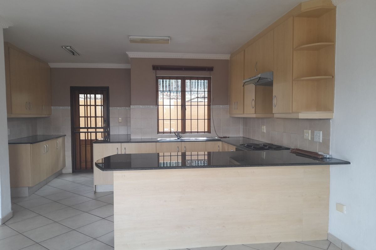 Spacious kitchen featuring light wood cabinetry, dark granite countertops, a breakfast nook, and a built-in hob with an extractor fan.