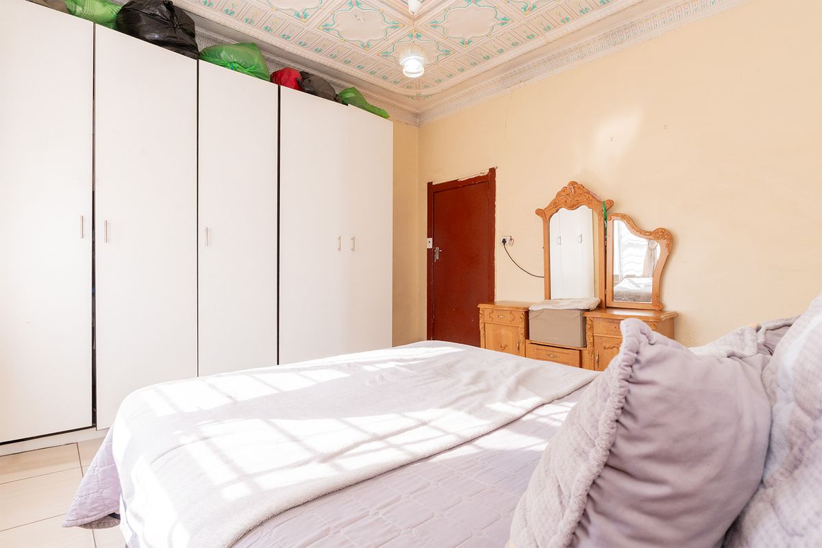 Bedroom featuring a decorative ornate ceiling, built-in wardrobe storage, and tiled flooring, offering a classic layout ready for cosmetic updates.