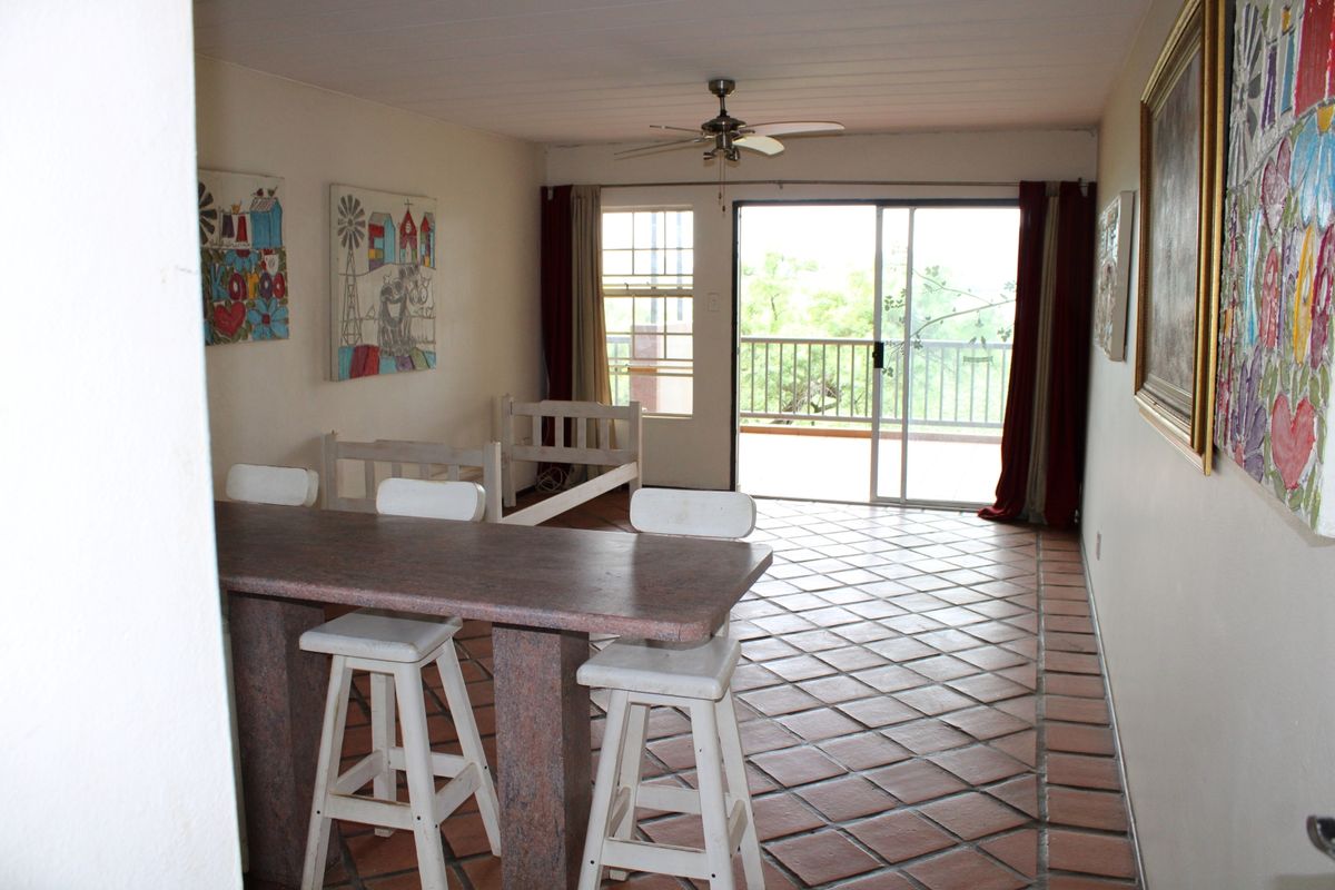 Spacious living area featuring terracotta floor tiles, a ceiling fan, and sliding glass doors leading to an outdoor balcony.