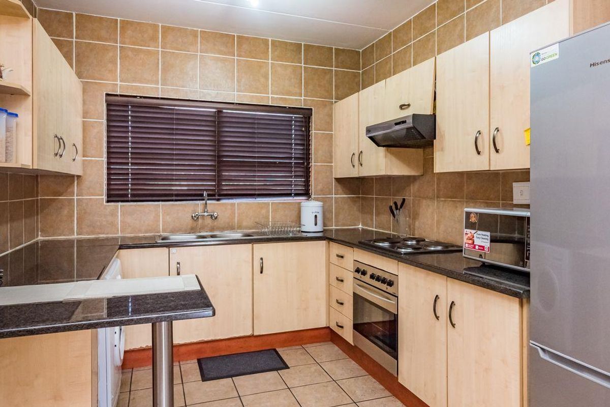 A functional kitchen featuring light wood cabinetry, dark granite countertops, tiled backsplash, built-in oven, hob, and extractor fan.