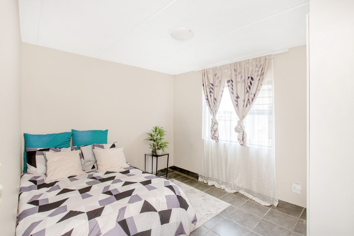 A bedroom featuring tiled flooring, a window with curtain tracks, and a ceiling-mounted light fixture.