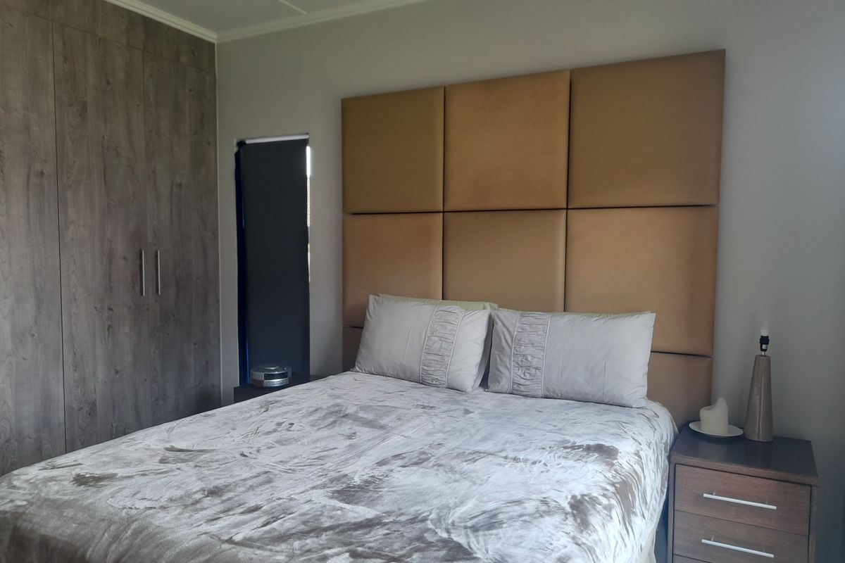 A well-maintained bedroom featuring built-in wood-grain cabinetry and a large upholstered headboard wall panel.