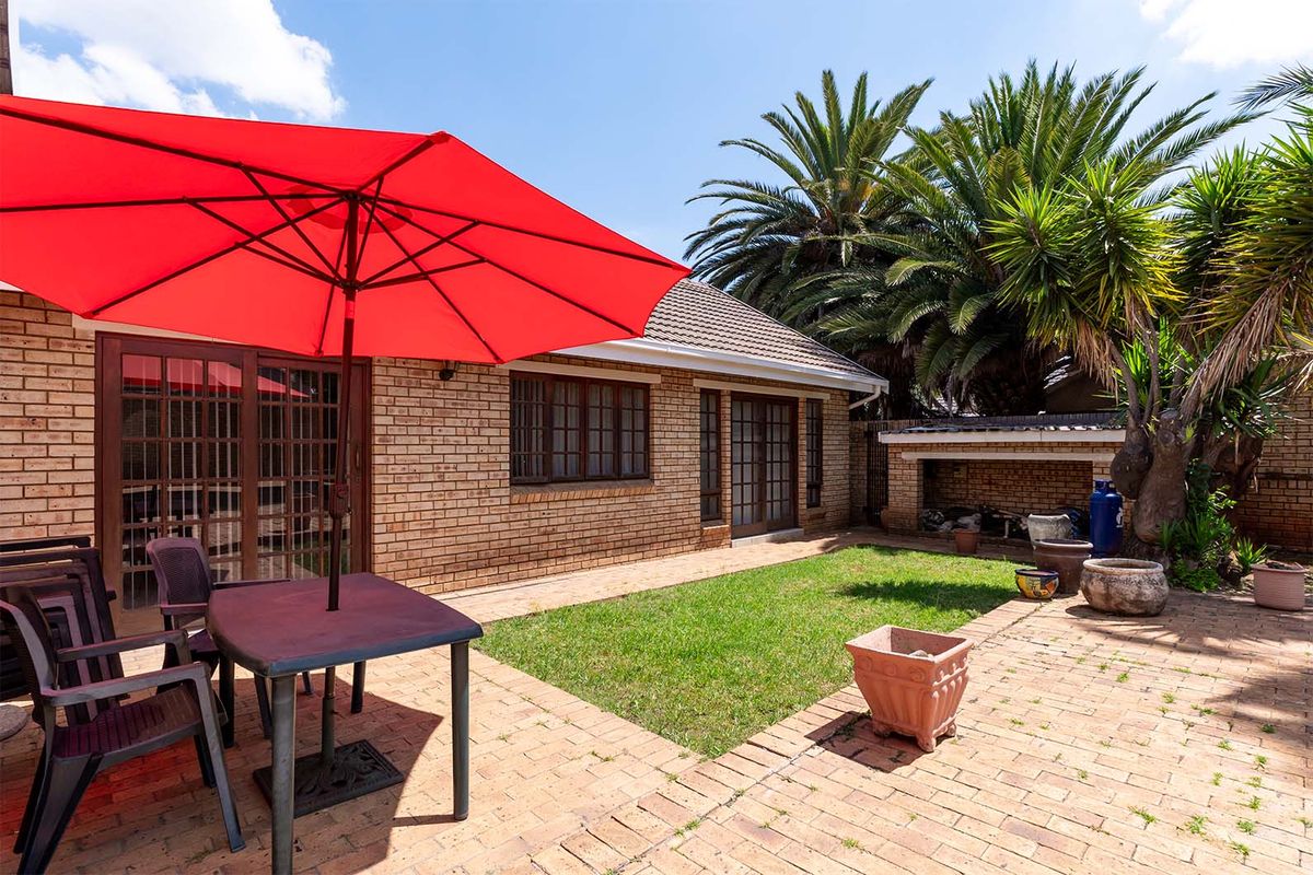 A private rear garden featuring a paved patio area, a built-in braai, and direct access to the home through sliding doors.