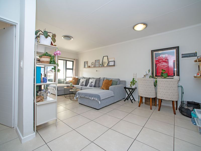 A bright and spacious living room featuring neutral tiled flooring and a large sliding glass door providing natural light.