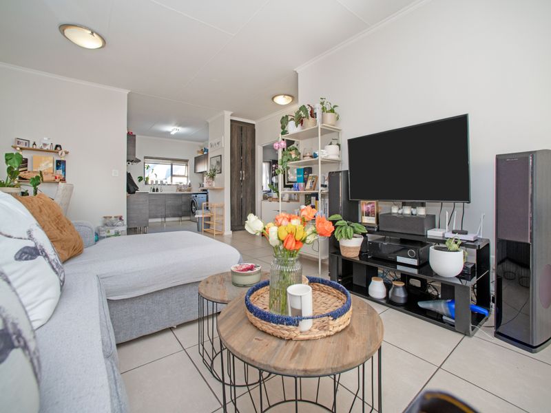 Open plan living area featuring tiled flooring and a connected kitchen space with built-in cabinetry and storage.