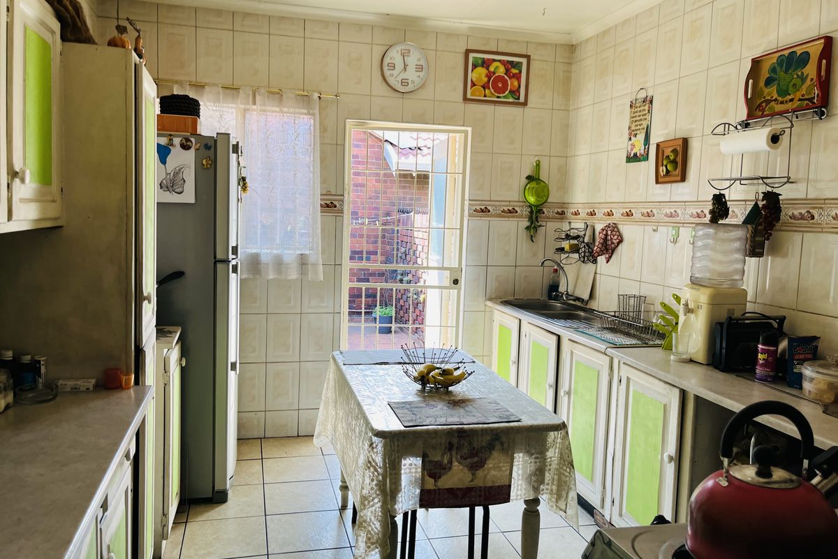 A functional kitchen featuring tiled walls and flooring, built-in cabinetry, and direct access to an exterior courtyard area.