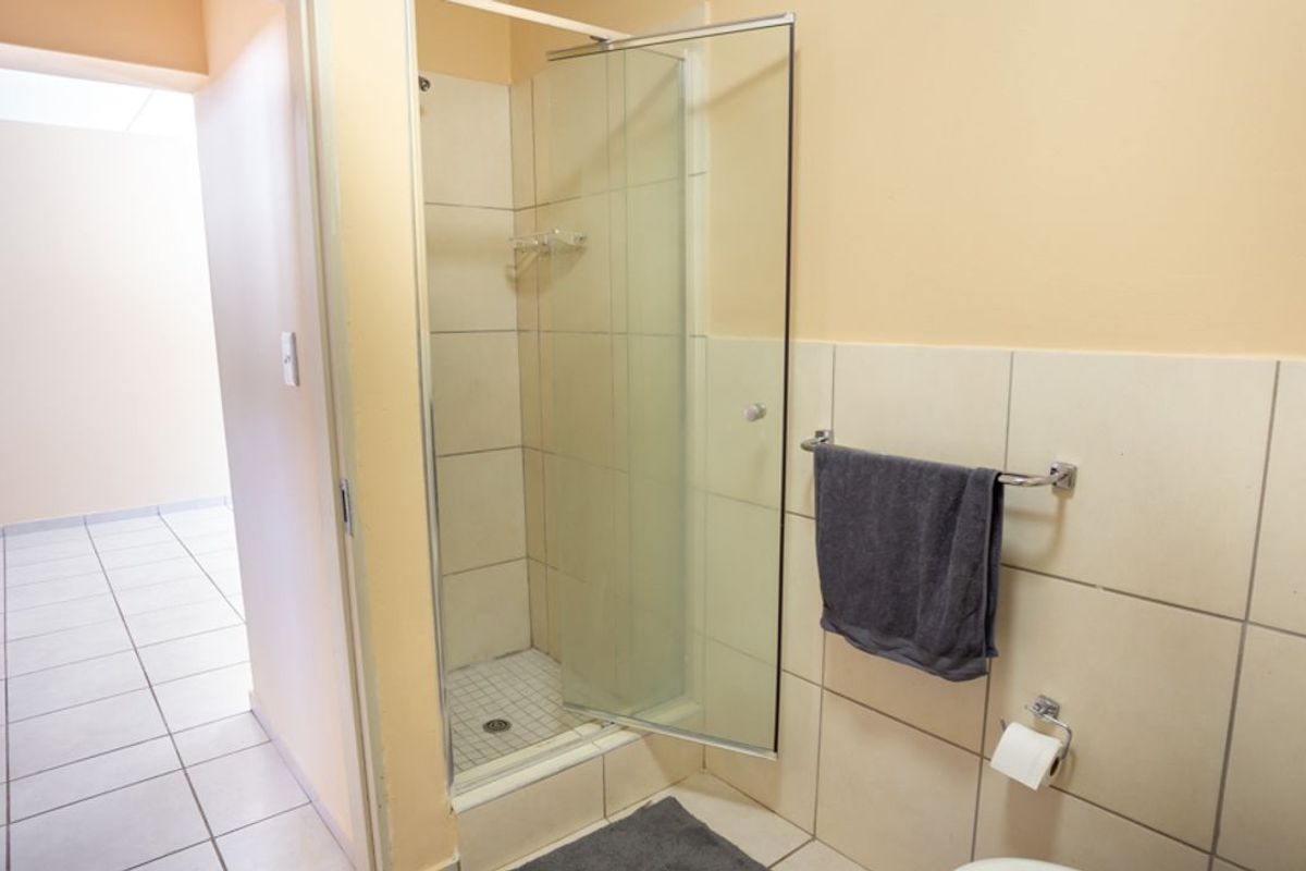 A functional bathroom featuring a glass-enclosed shower, tiled walls, and standard fixtures, providing a clean and practical space.