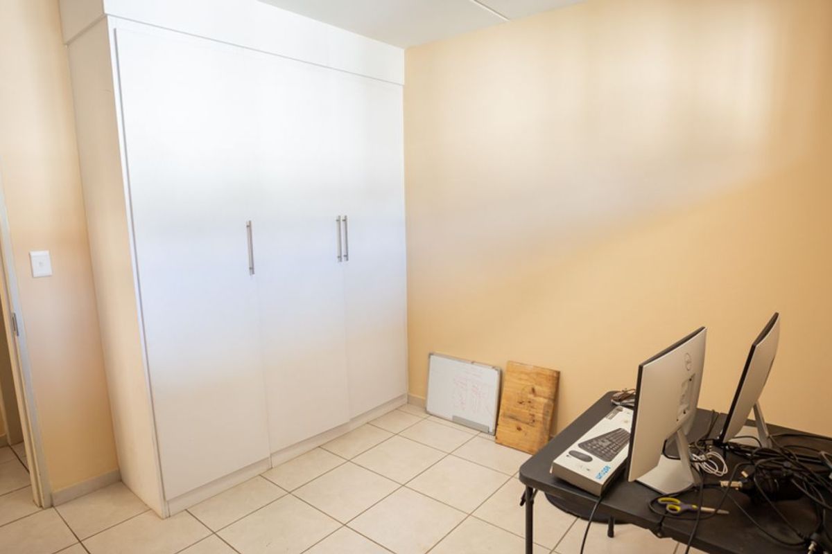 A functional bedroom featuring built-in white cabinetry and tiled flooring, suitable for use as a home office or guest room.