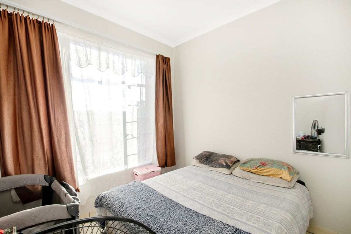 A functional bedroom featuring a large window with curtains, providing natural light to the space.