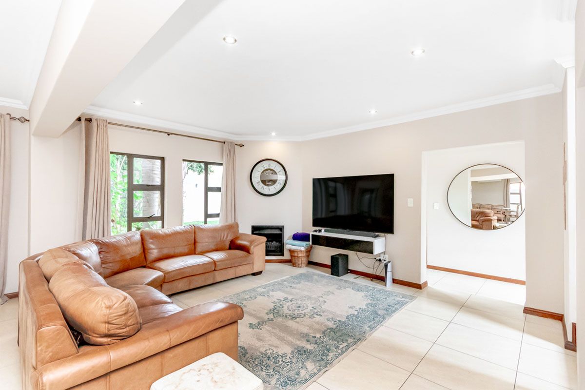 Spacious living room featuring tiled flooring, recessed ceiling lighting, and a built-in fireplace, offering a bright and comfortable area for relaxation.