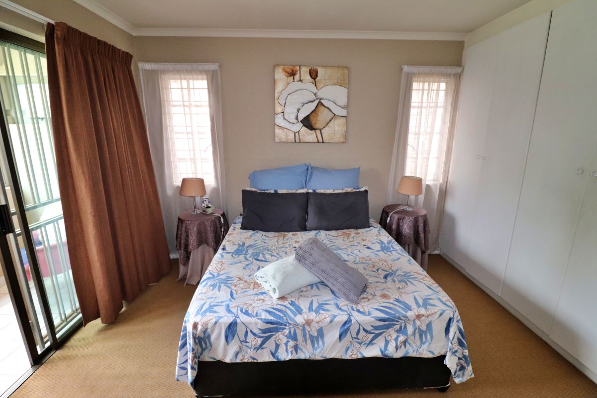 A bedroom featuring built-in cupboards, carpeted flooring, and sliding glass doors providing access to an outdoor balcony area.