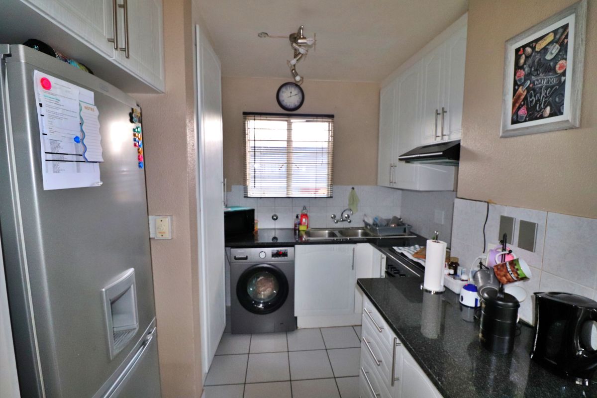 Compact kitchen featuring white cabinetry, dark granite countertops, tiled flooring, and integrated laundry plumbing for a washing machine.