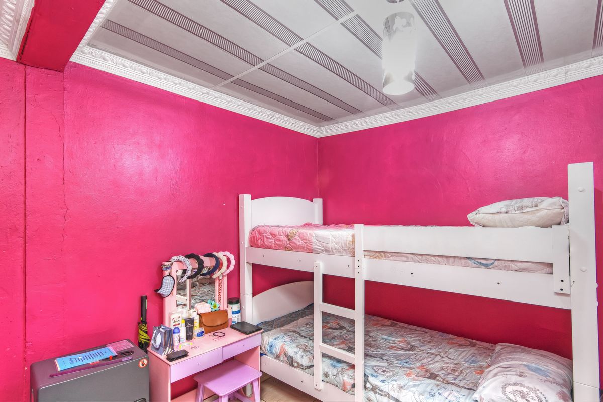 A bedroom featuring bright pink walls and a decorative ceiling finish, providing a vibrant space for occupants.