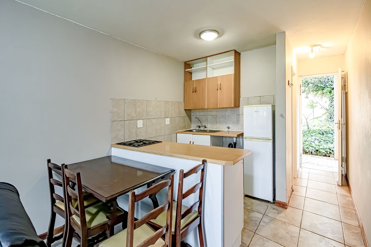 Compact kitchen area featuring built-in cabinetry, a hob, and tiled backsplash, with direct access to an outdoor space.