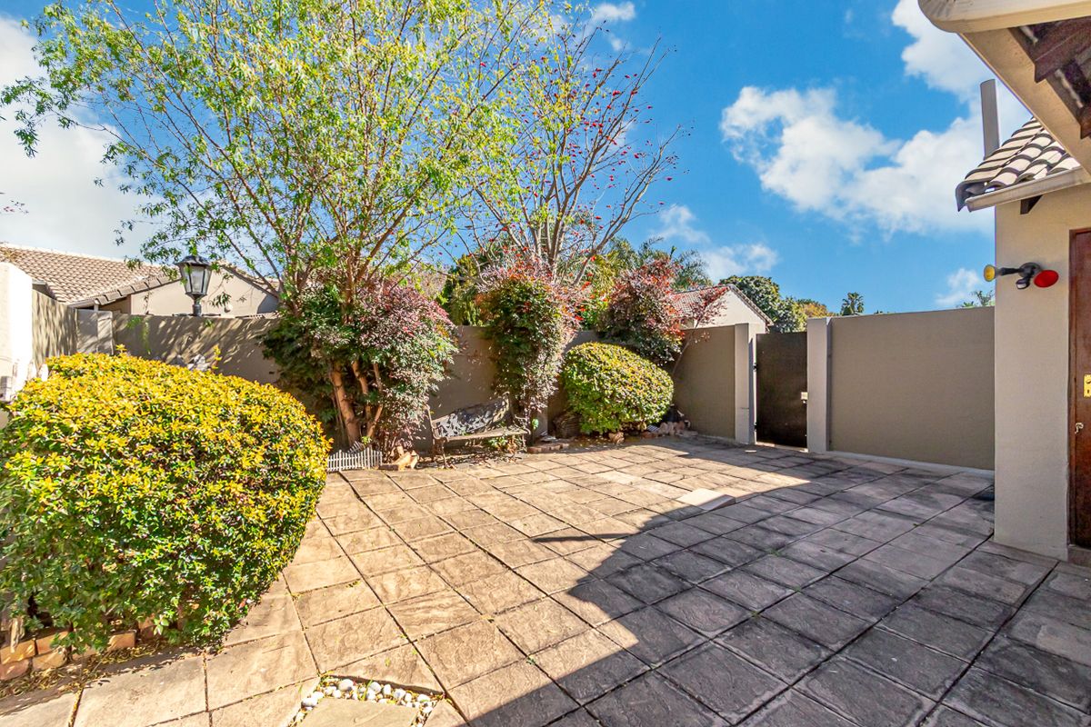 A private paved courtyard area featuring perimeter boundary walls, established garden shrubs, and direct access to the main dwelling.