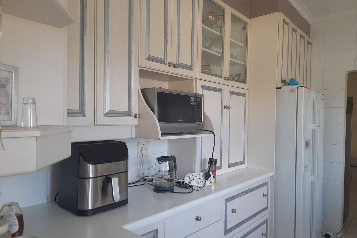 A functional kitchen area featuring built-in cabinetry with glass-front display units, ample counter space, and a dedicated microwave nook.