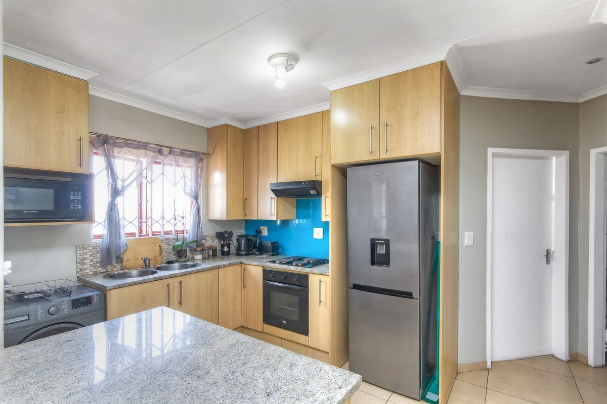 Functional kitchen featuring light wood cabinetry, granite countertops, built-in oven, hob, extractor fan, and integrated microwave with tiled flooring.