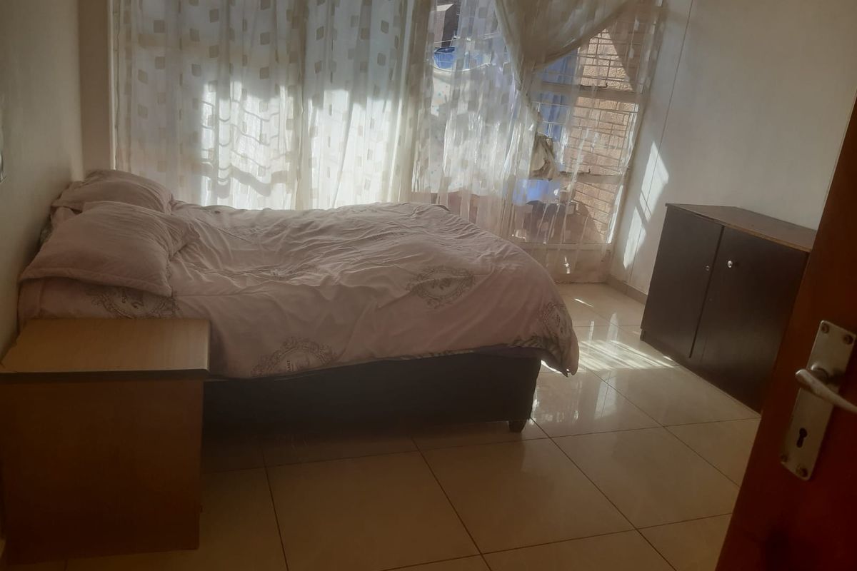 A bedroom featuring tiled flooring and large windows with natural light, providing a functional and bright living space.