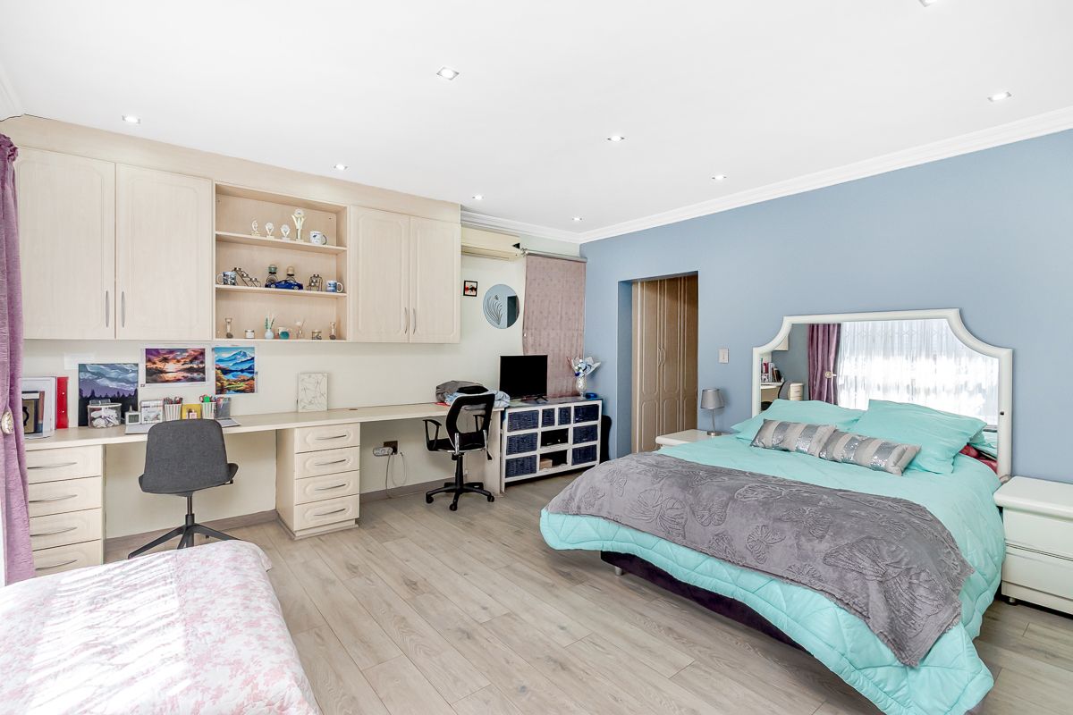 Spacious bedroom featuring built-in cabinetry, integrated desk workspace, recessed downlighting, and light-toned wood-look flooring.