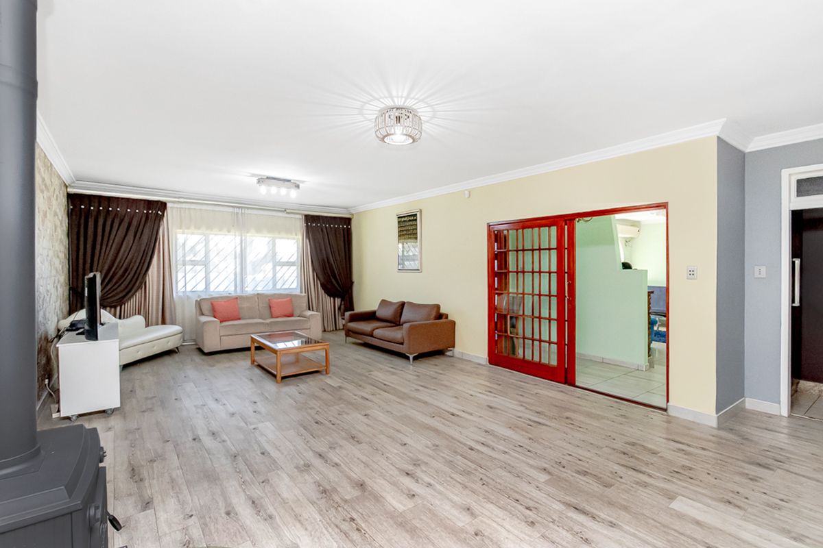 Spacious living room featuring wood-look laminate flooring, a built-in fireplace, and a distinctive red-framed sliding door leading to an adjacent room.