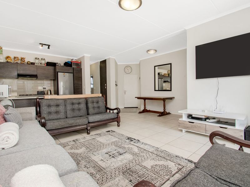 Open-plan living area featuring tiled flooring, recessed lighting, and an integrated kitchen with dark cabinetry, creating a functional and connected living space.