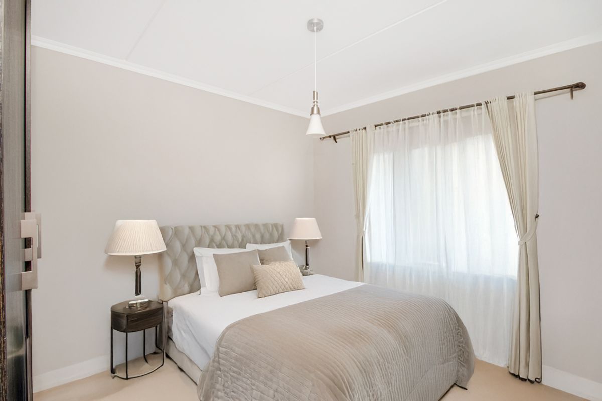 A well-maintained bedroom featuring neutral wall tones, coving, and a window fitted with a curtain rod.