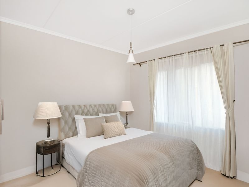 A well-maintained bedroom featuring neutral wall tones, coving, and a window fitted with a curtain rod.