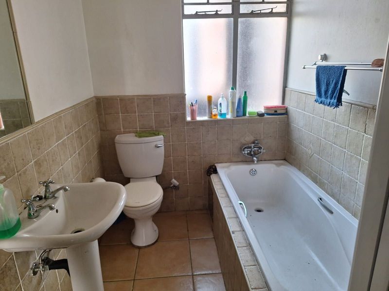 A functional bathroom featuring a pedestal basin, standard toilet, and a built-in bathtub with tiled wall and floor finishes.