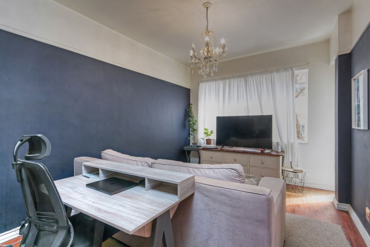 A living room featuring dark accent walls, hardwood flooring, and a decorative chandelier, providing a cozy and functional living space.