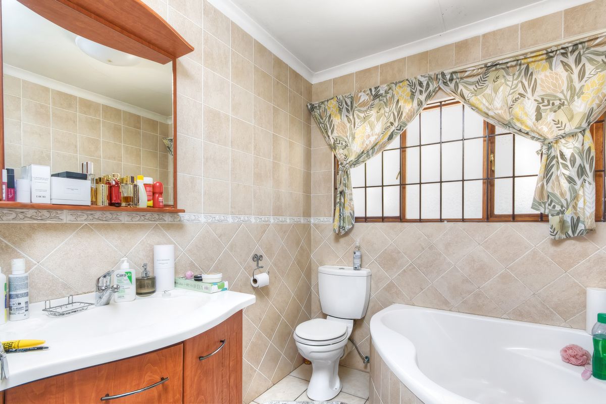 A functional bathroom featuring a built-in vanity with basin, a standard toilet, and a bathtub with tiled wall finishes.
