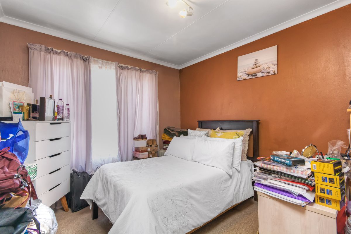 A standard bedroom featuring carpeted flooring, a window with curtain tracks, and a painted accent wall.