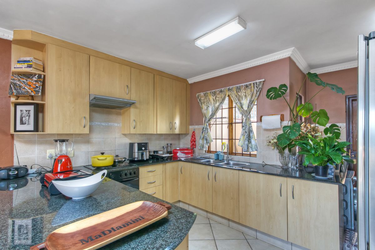 Functional kitchen featuring light wood cabinetry, dark granite countertops, a built-in stove with extractor fan, and a double basin sink.