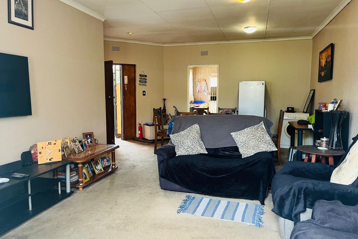 A living room area featuring carpet flooring and ceiling lighting, providing a functional space with potential for modernization and cosmetic updates.