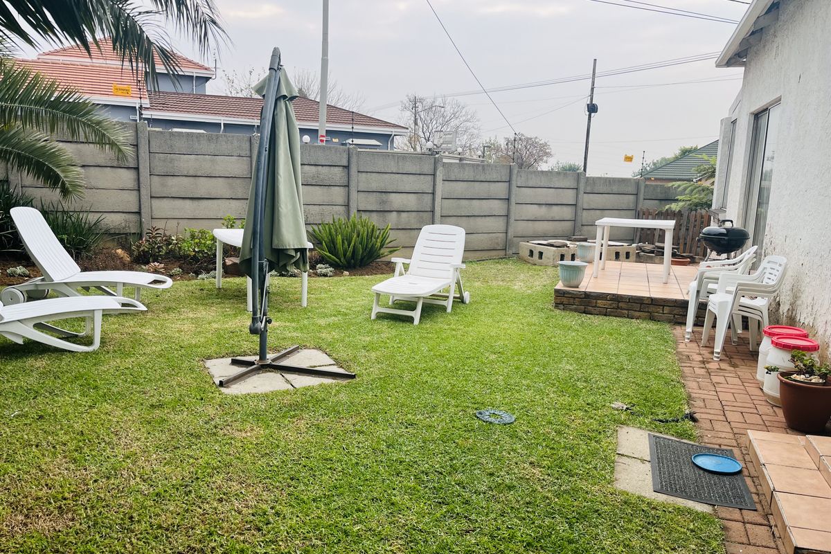 A private rear garden featuring a small paved patio area, established lawn, and perimeter boundary walling.