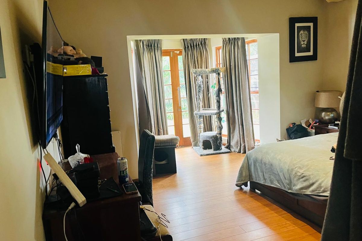 Spacious bedroom featuring laminate flooring, air conditioning unit, and double glass doors providing direct access to the outdoor area.