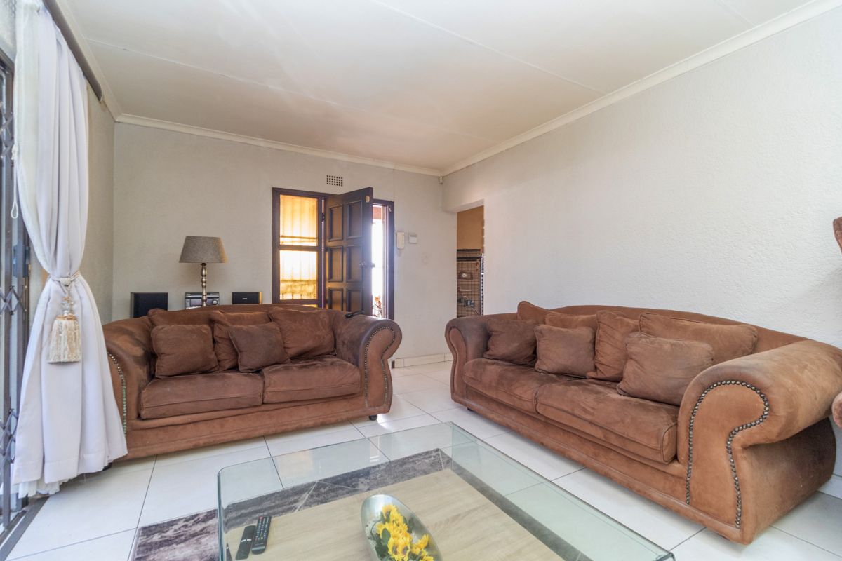 A spacious living room featuring tiled flooring, neutral walls, and direct access to an exterior entrance.