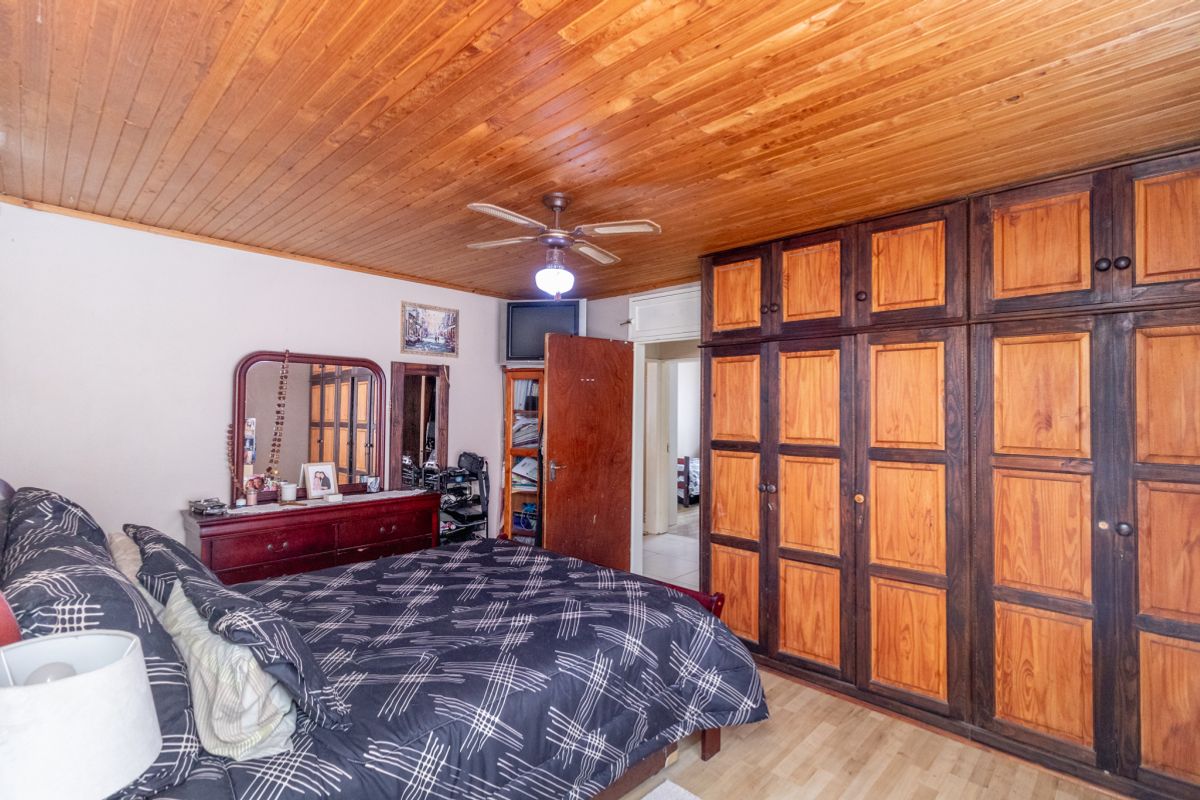 A bedroom featuring a timber-clad ceiling, built-in wooden wardrobes, and laminate flooring.