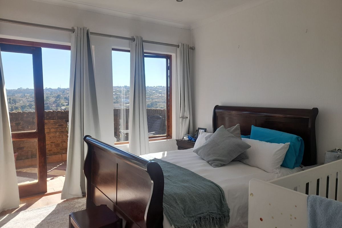 A bright bedroom featuring large windows and a glass door leading to a private balcony with scenic views.