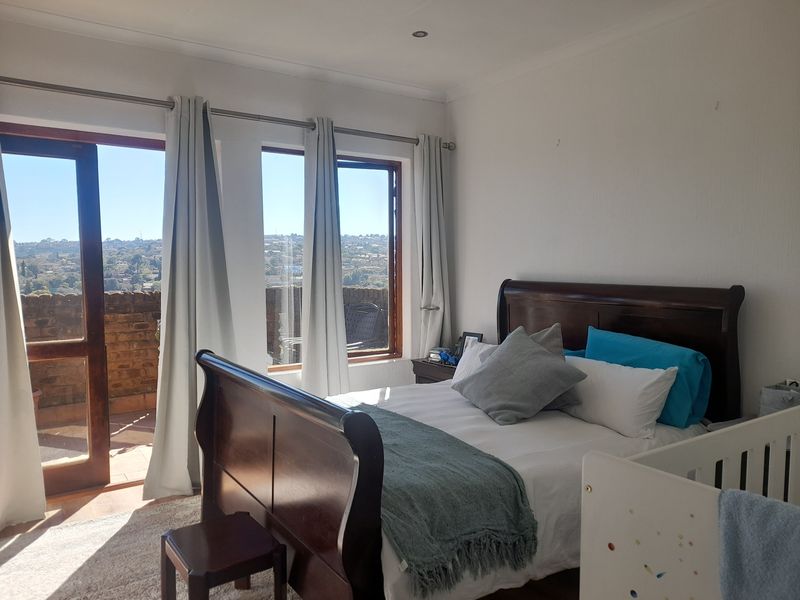 A bright bedroom featuring large windows and a glass door leading to a private balcony with scenic views.