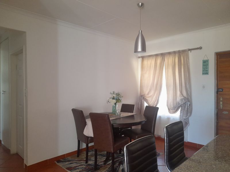 A dining area featuring tiled flooring, a pendant light fixture, and a window with curtain rod.