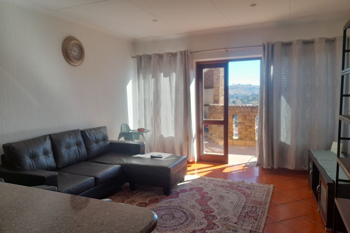 A bright living room featuring terracotta floor tiles and direct access to a balcony with scenic views.