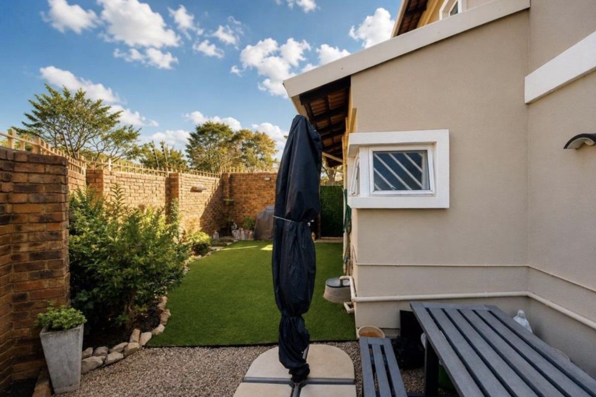 A private rear garden featuring a low-maintenance artificial lawn, perimeter brick walling, and a paved patio area adjacent to the building exterior.
