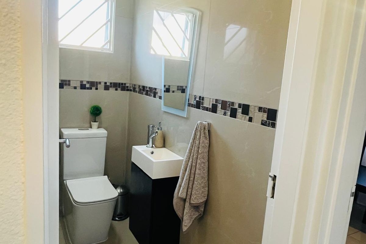 A compact guest bathroom featuring modern wall tiling, a sleek vanity basin, and a contemporary toilet suite.