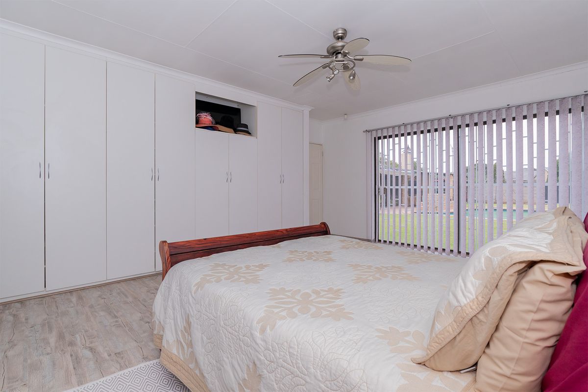 Spacious bedroom featuring extensive built-in cabinetry, a ceiling fan, and sliding glass doors providing direct access to the outdoor area.