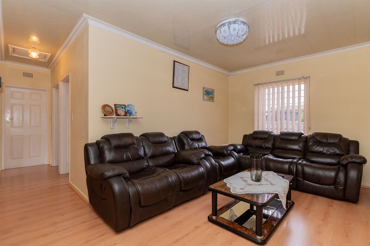A living room featuring laminate flooring, ceiling cornice, and vertical blinds, providing a functional and well-maintained space.