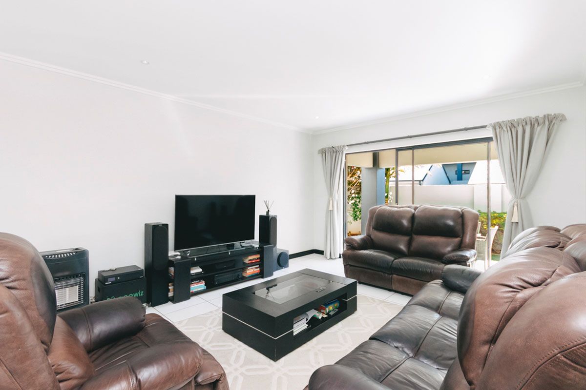 Spacious living room featuring tiled flooring and large sliding glass doors that provide direct access to the outdoor patio area.