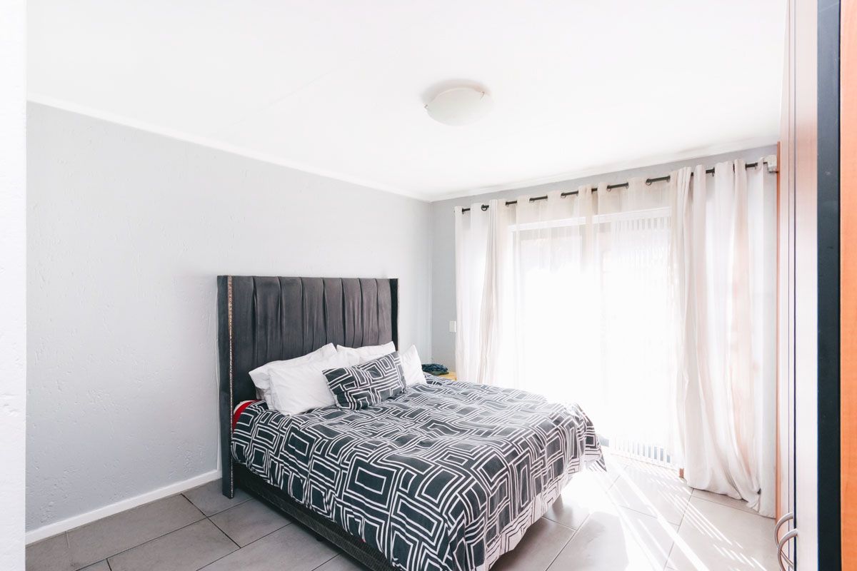A bright bedroom featuring tiled flooring and a sliding glass door providing access to an outdoor area.